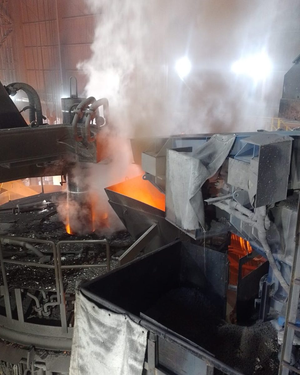 Scorifica del forno elettrico con siviera piena di acciaio liquido e fumi